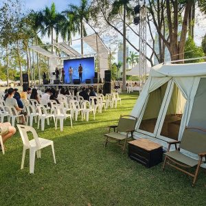 Outdoor camping tent set up beside an open-air event stage on a grass field, showcasing a campsite display scene.