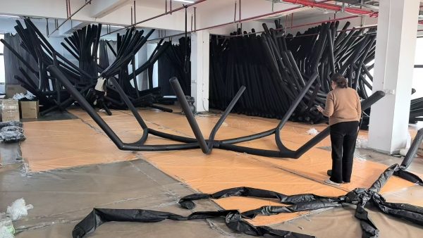 Factory worker assembling inflatable air beam structure for custom inflatable tent production