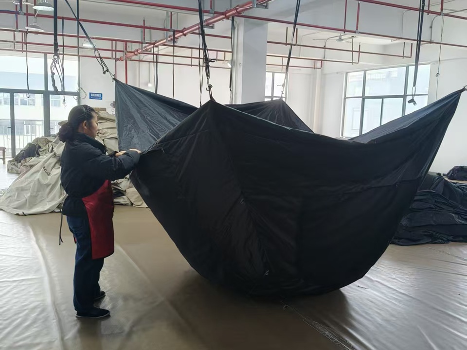 Worker performing final quality inspection on a camping tent before packaging and shipment
