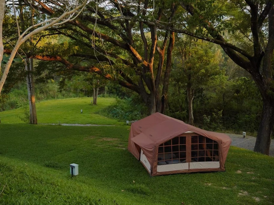 Customer-installed NastoCamp glamping tent set up in a natural outdoor camping environment surrounded by trees and greenery.