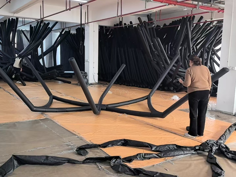 Workers inspecting inflatable tent beams during quality verification at NastoCamp in March 2026