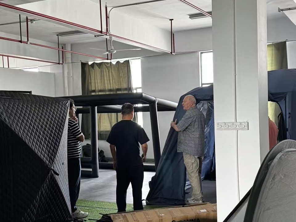 Swiss customer evaluating multiple tent models during a factory showroom visit at NastoCamp.