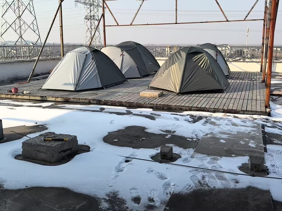 Camping tents prepared for rain testing during winter conditions at NastoCamp in January 2026