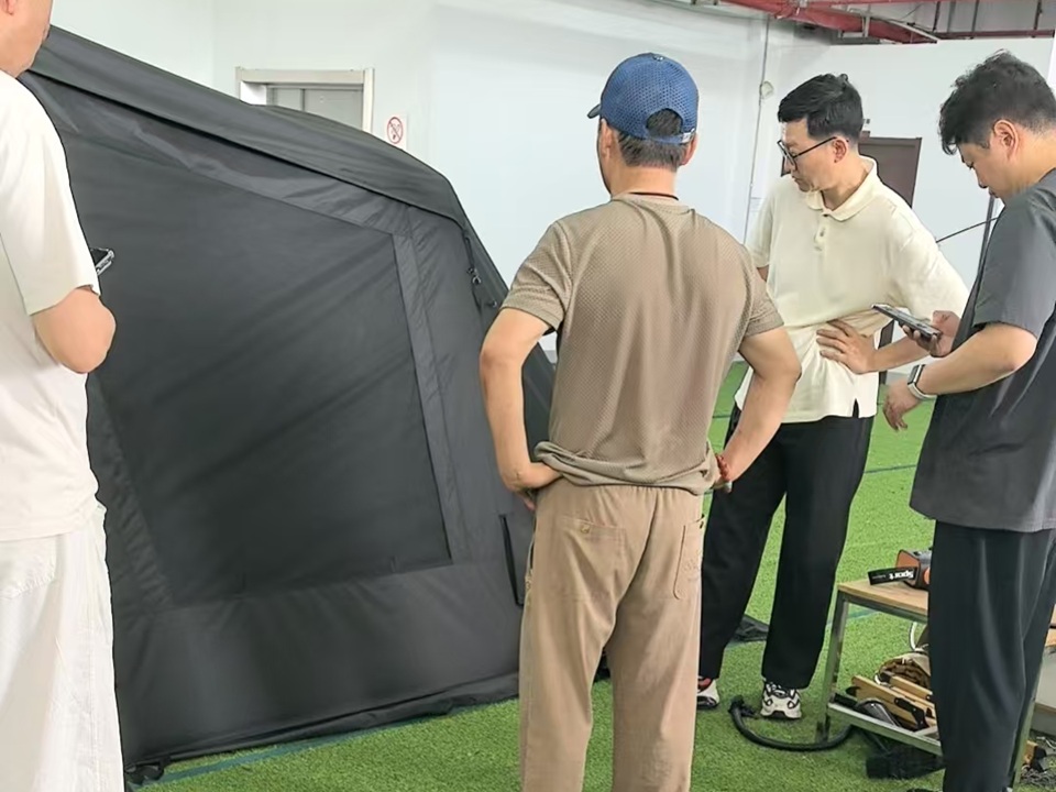 Korean customer reviewing new inflatable tent models with the NastoCamp team during a factory product evaluation and development meeting.