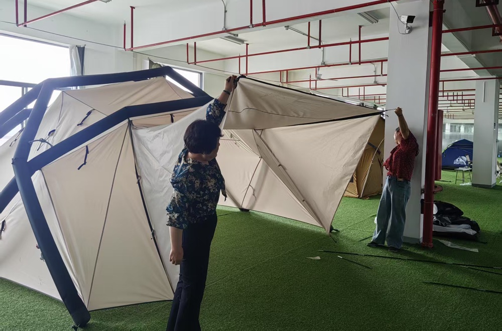 NastoCamp team checking an assembled inflatable tent at the factory