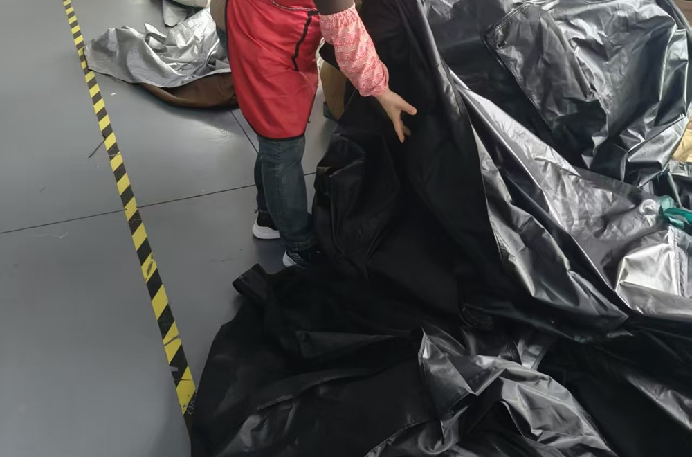 Workers preparing tent floor materials during camping tent production