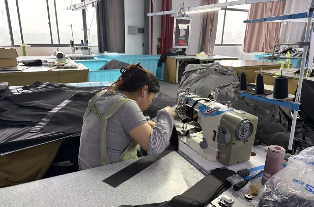 Worker sewing tent fabric at the NastoCamp manufacturing facility