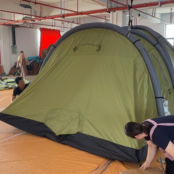 Workers adjusting a large tent set up inside a manufacturing workshop