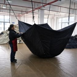 Worker performing in-process quality control inspection on tent during manufacturing